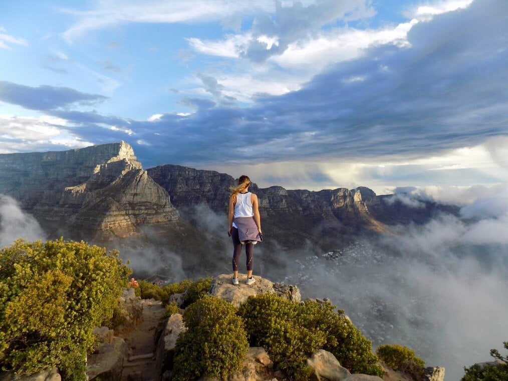 Girl standing on a cliff looking at sky