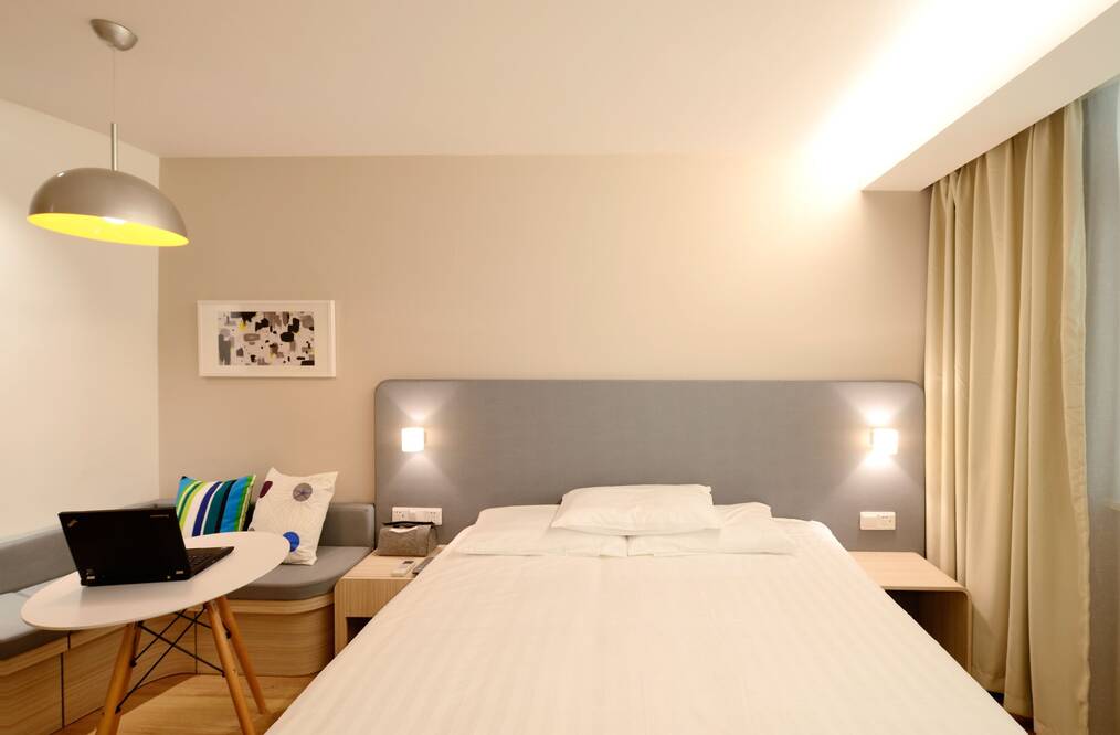 Bedroom with white bed in center and table for laptop