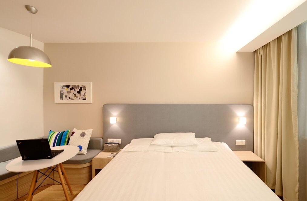 Bedroom with white bed in center and table for laptop
