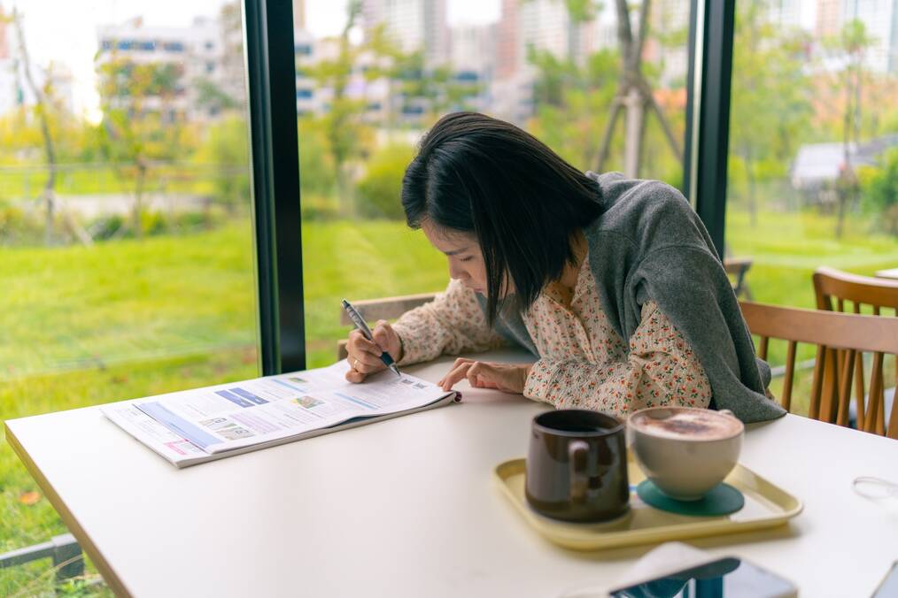 Person at a cafe studying and writing on a piece of paper
