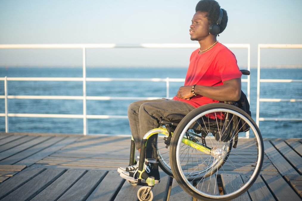 Person sitting in wheelchair on bridge over water