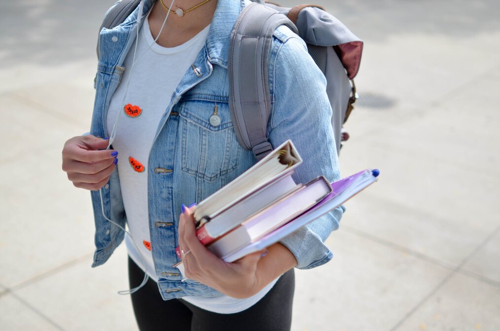 Person at school carrying textbooks and notebooks