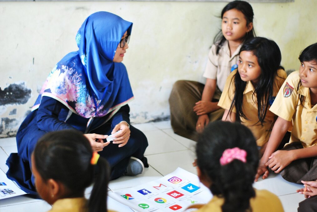 Teacher sitting on the floor with students