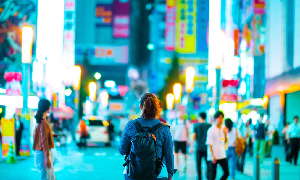 Traveler walking through a crowded city, neon lights, wearing a backpack