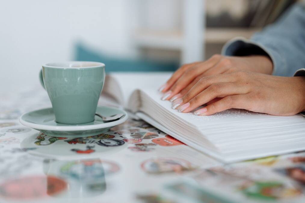 Hands, book, mug, person reading braille