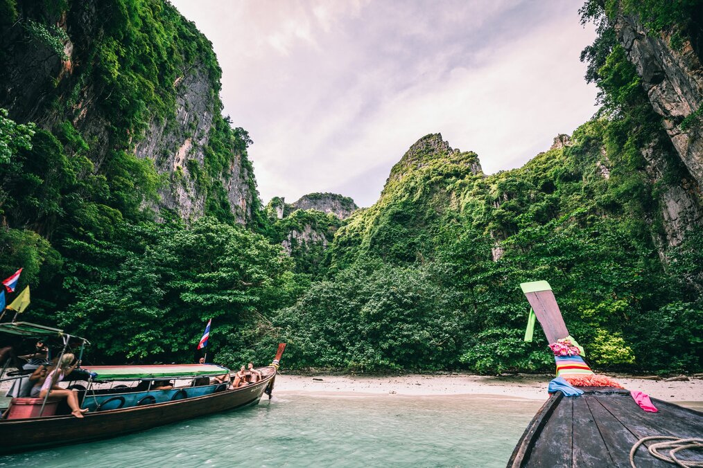 People in boats docked on the water, green hills