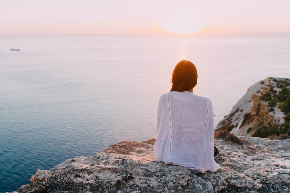 Person sitting on rock overlooking water
