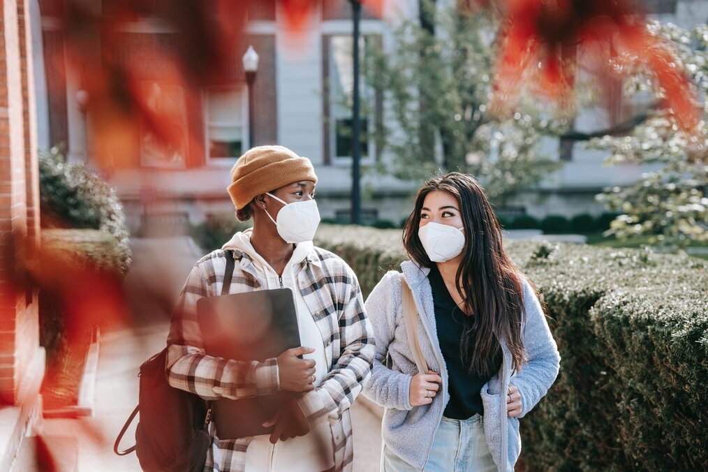 Two students walking through campus wearing masks