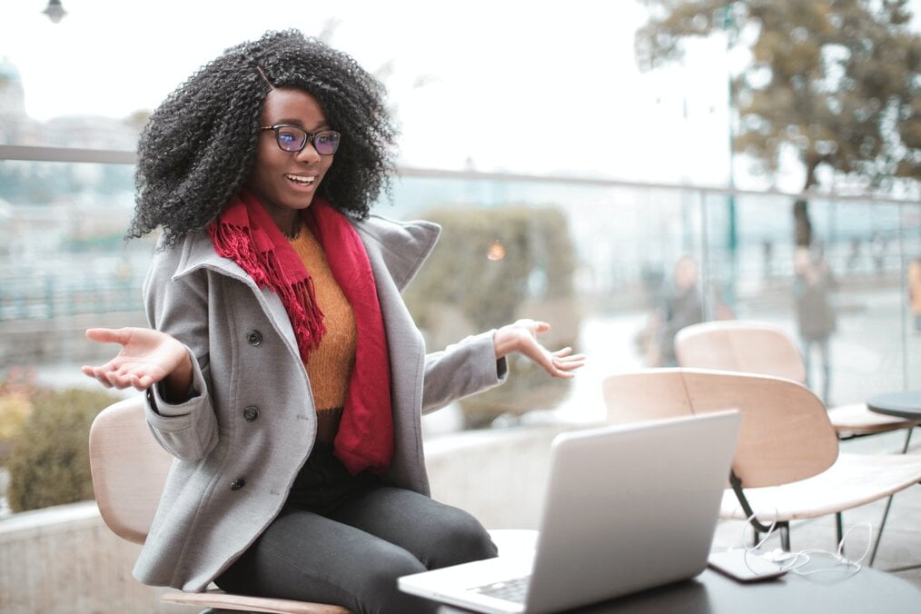 Person sitting down hands up teaching students on laptop