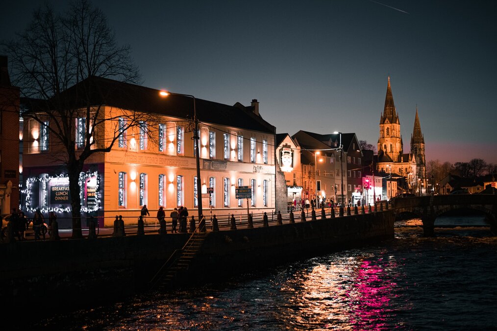 Photo by 2sometravel on Unsplash Buildings along a river at night in Cork, Ireland.