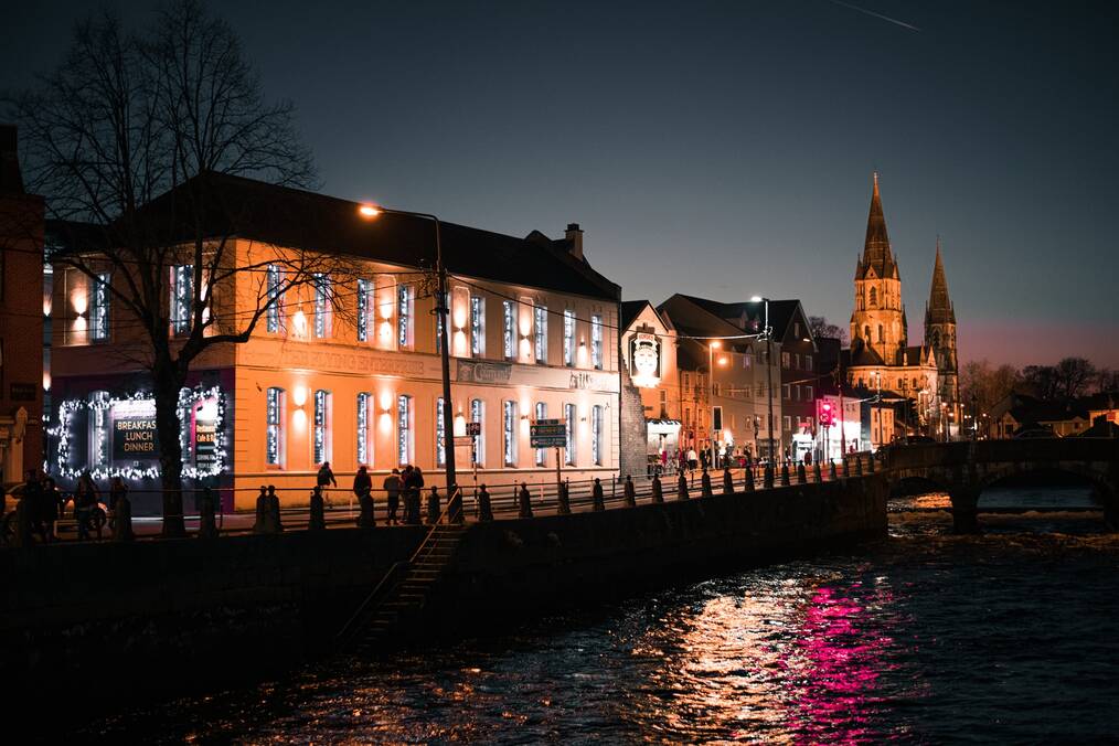 Buildings along a river at night in Cork, Ireland.