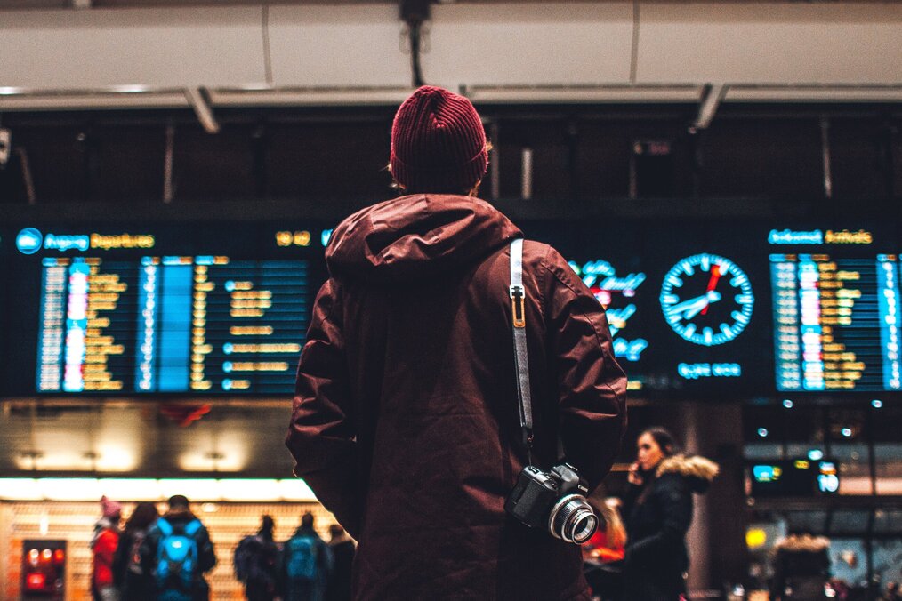 Person at an airport standing in front of departure screens