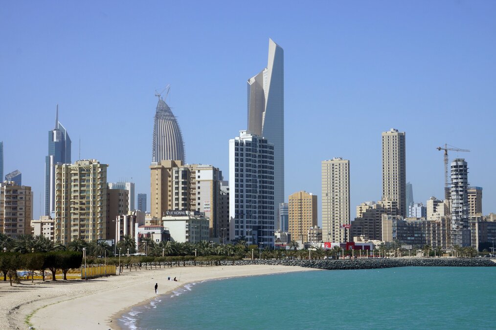 A white sand beach with Kuwait City in the background.