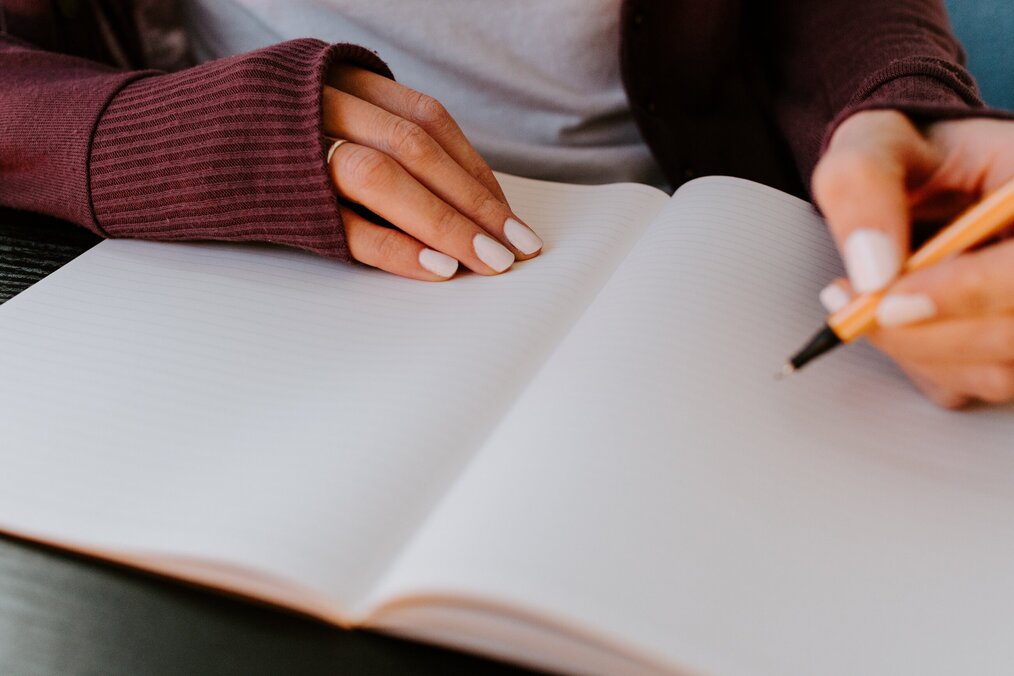 Person writing in notebook using pencil