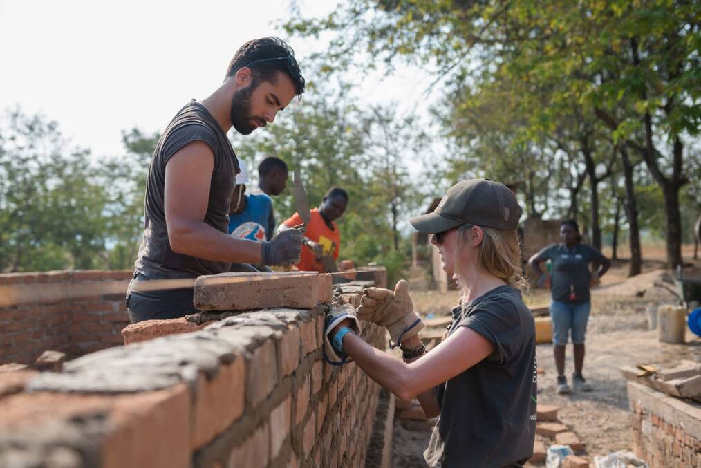 Volunteers building a brick wall