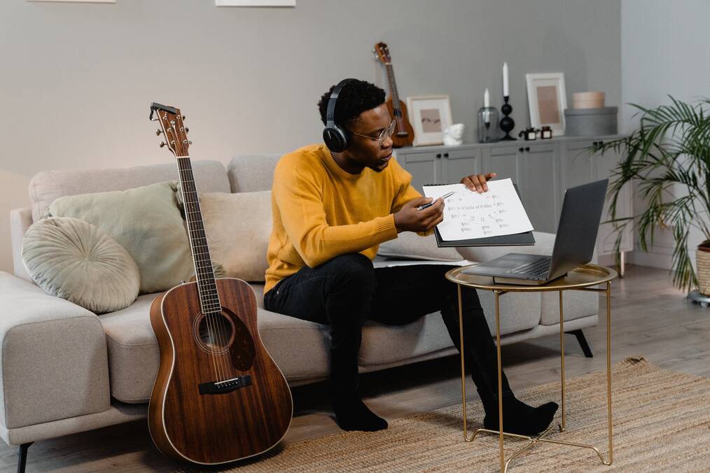 An online ESL teacher sitting on the couch teaching to his computer