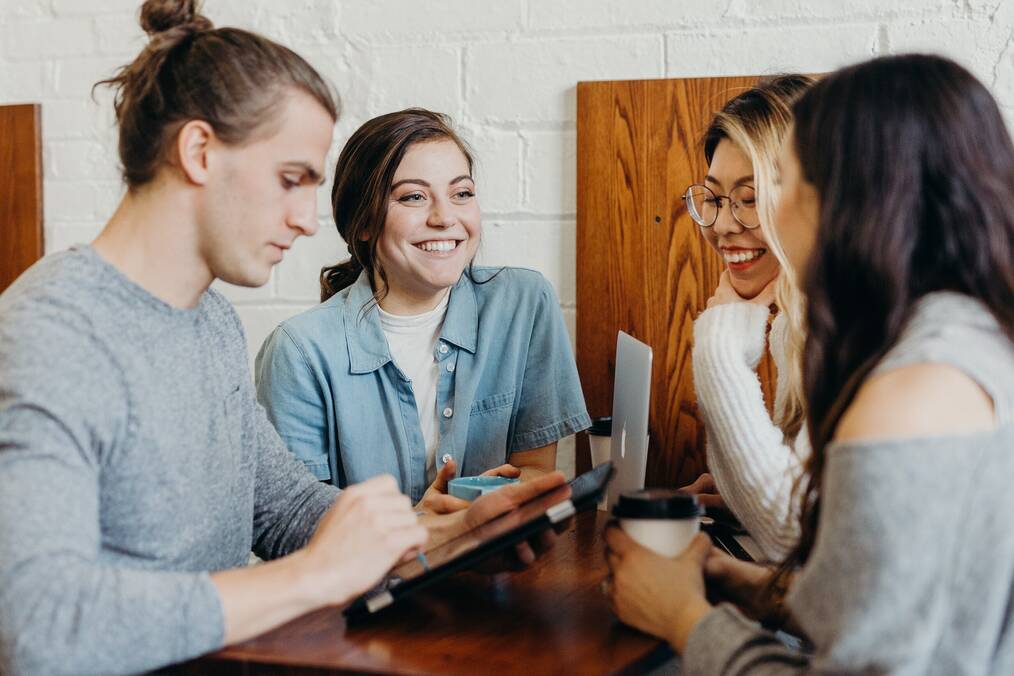 Four students sitting around a table smiling.