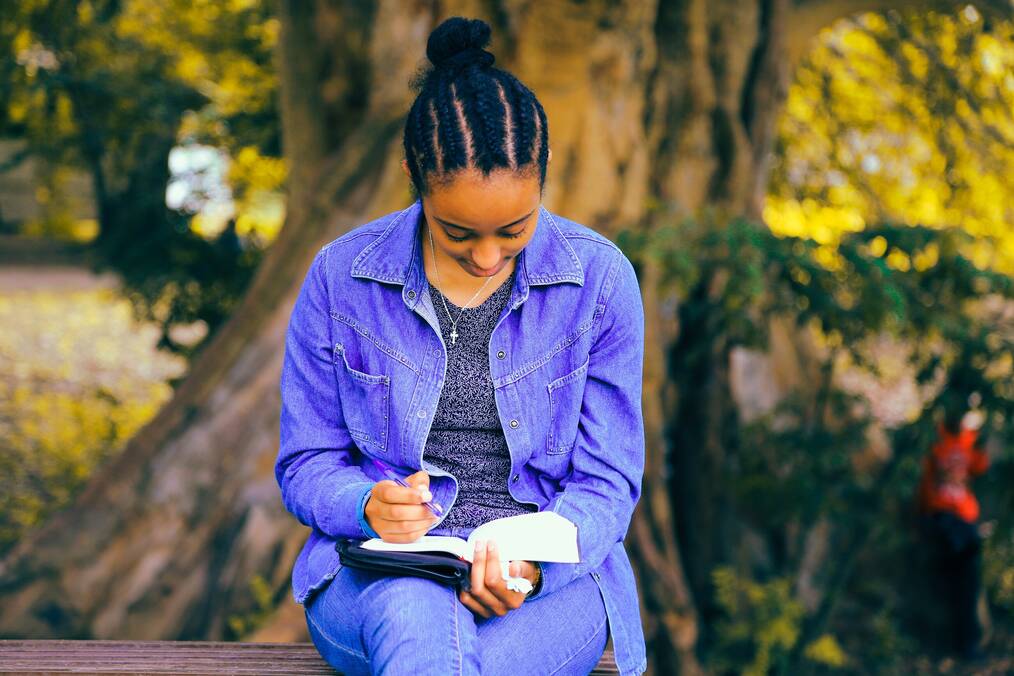 A woman sitting outside writing.