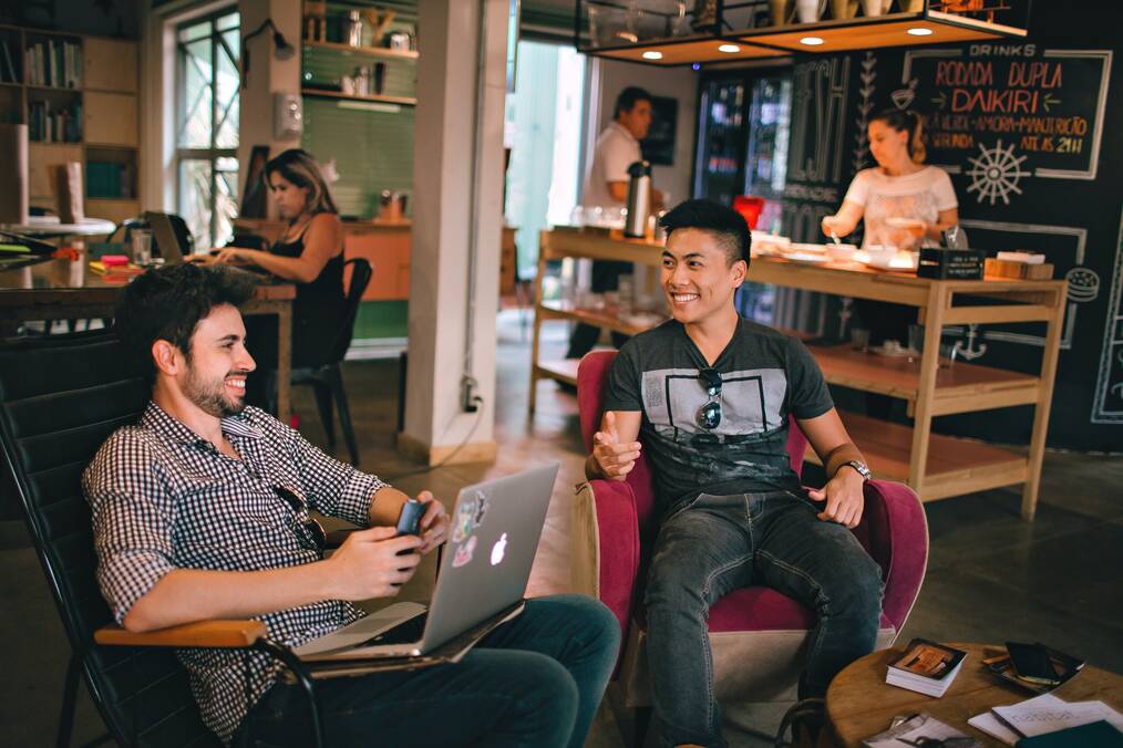 Two men talking and laughing in a cafe.