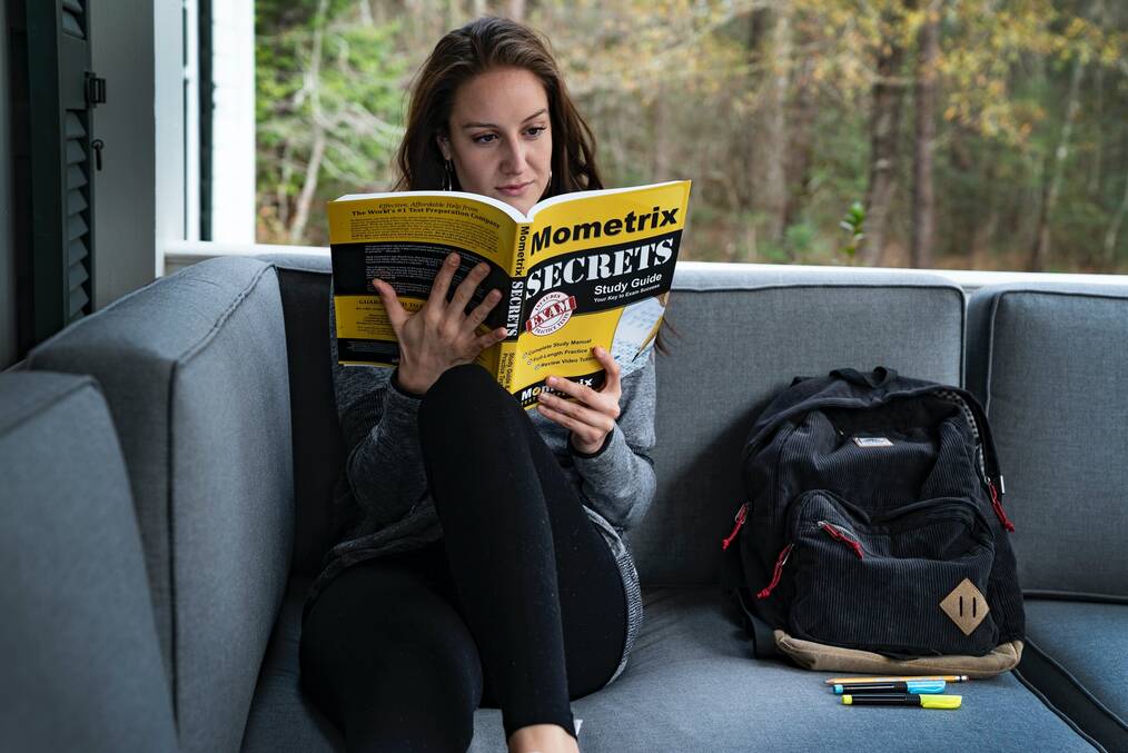 A woman reading a test prep book.