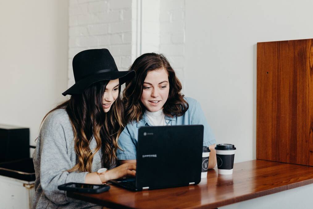 Two women looking at a laptop screen and smiling.