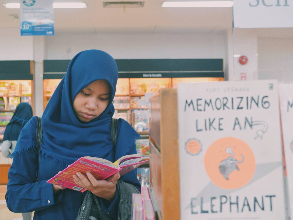 A woman standing in a store reading a book.