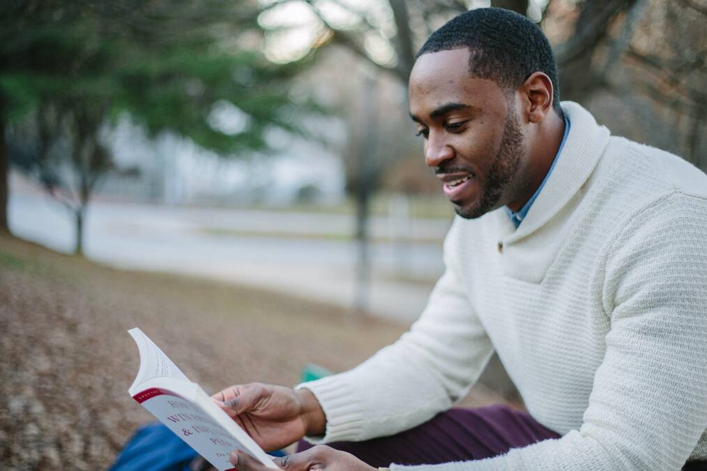 A man sitting outside reading a book.