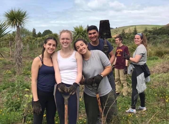 Mia D., IFSA New Zealand alum Mia smiling while working on a farm with friends in New Zealand