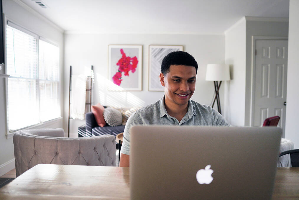 A young adult working on a MacBook 