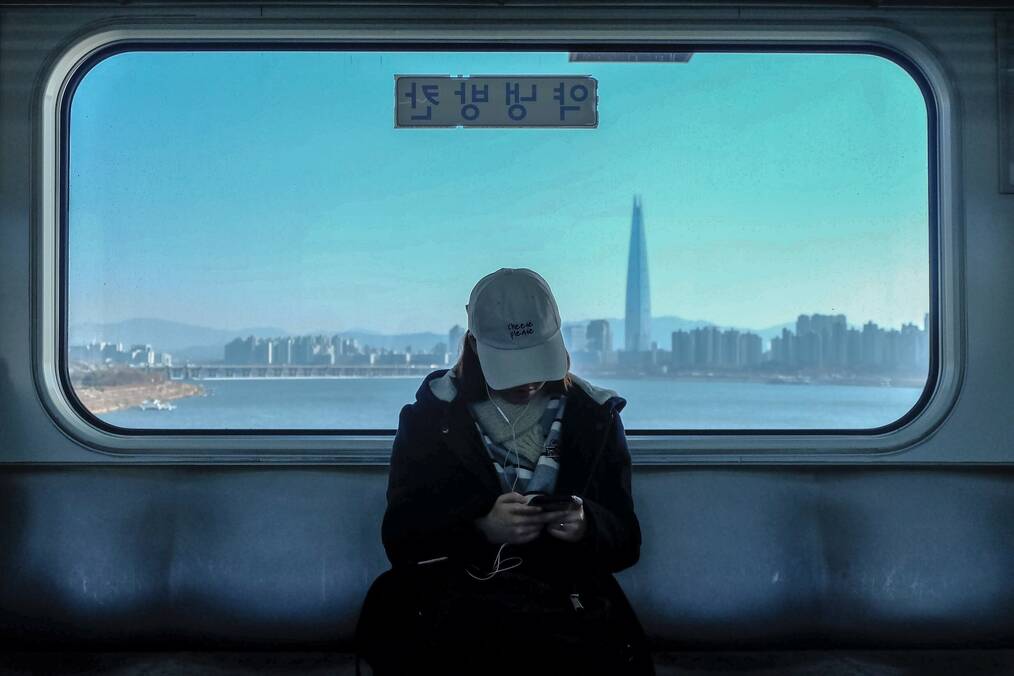 Woman sitting on Korean train with a city in the background.