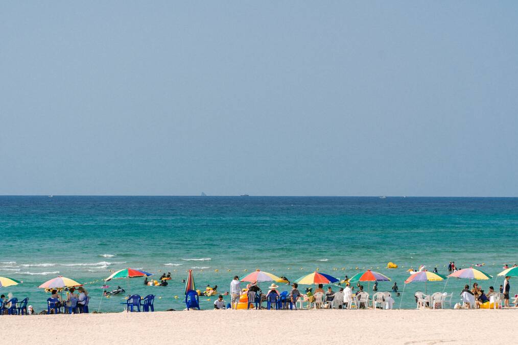 People on a white sand beach with clear blue water.