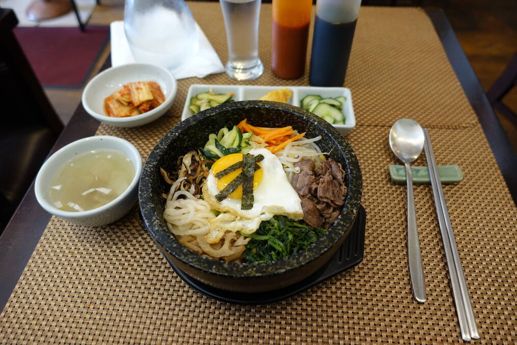 Korean Dolsot Bibimbap in a stone bowl on a table.