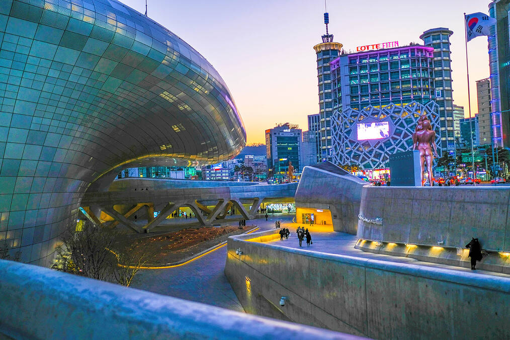 A geometric building in the foreground of a cityscape