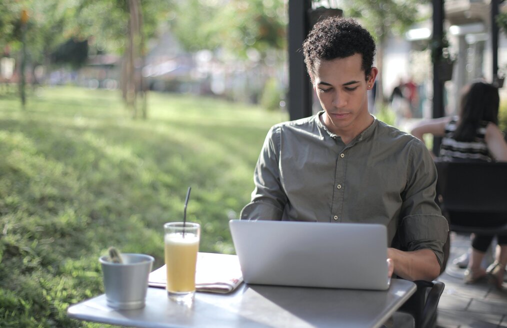 Image curtesy of Andrea Piacquadio, Pexels A man in a green shirt on his laptop outside at a cafe