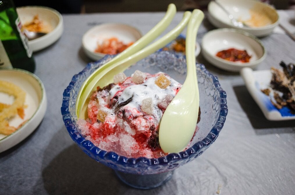 Photo by makafood A clear bowl with Korean bingsu shaved ice dessert inside.