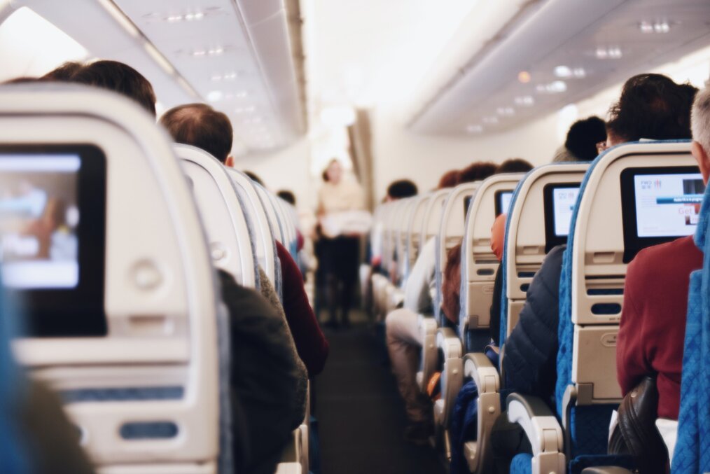 Image curtesy of Suhyeon Choi, Unsplash An isle in an airplane with the flight attendant giving instructions