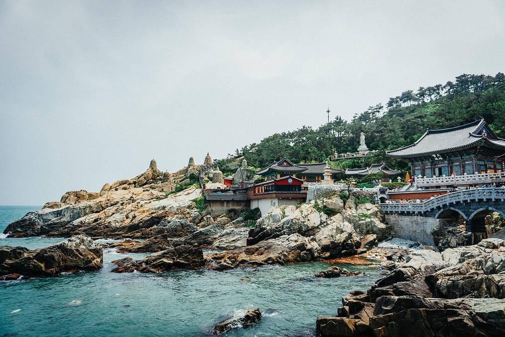 A rocky beach in Busan with historic buildings in the mid ground
