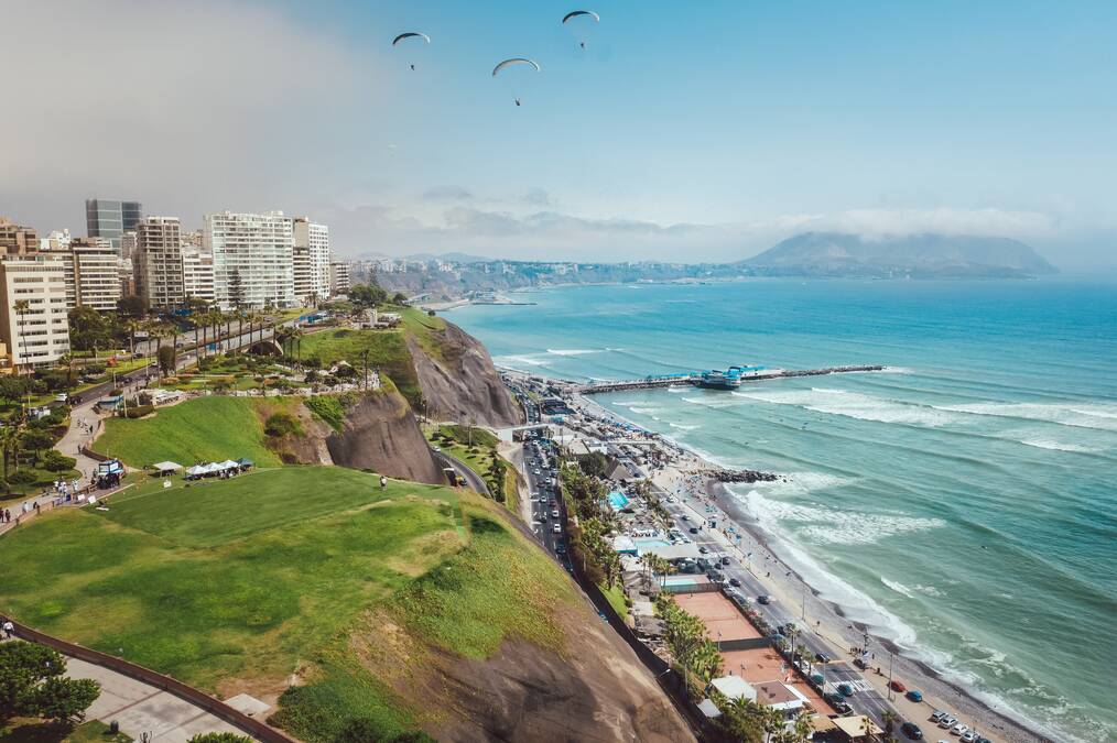 A city overlooking a blue ocean with mountains in the background.