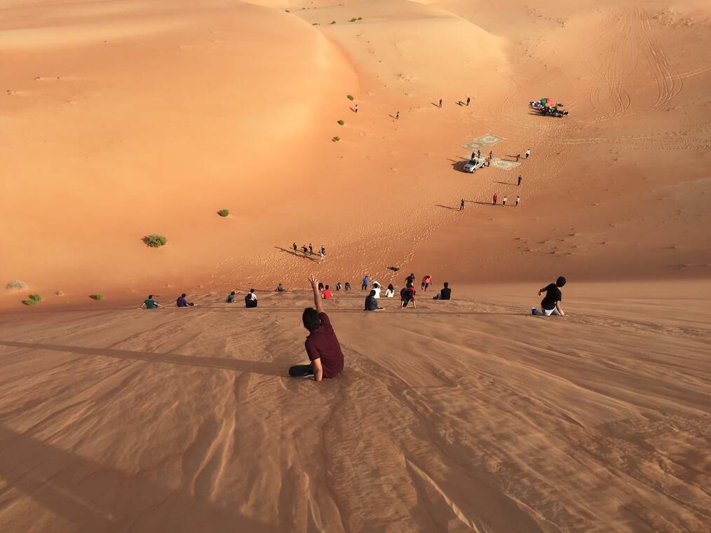 Children sliding down a desert hill in Dubai