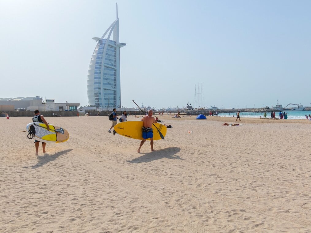 Image curtesy of Mostafa Meraji, Unsplash People walking on the beach in Dubai carrying stand up paddle boards
