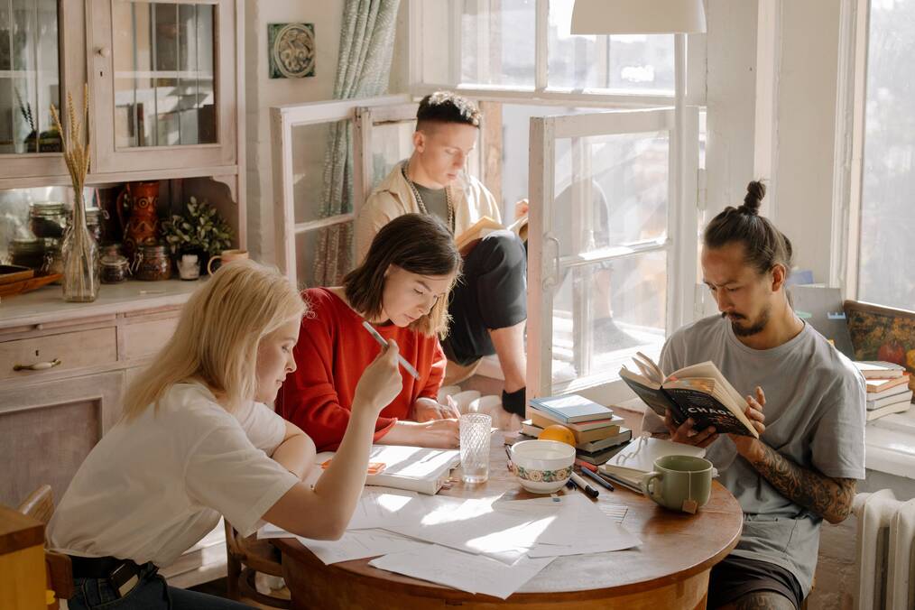 A group of people sitting around a table reading.