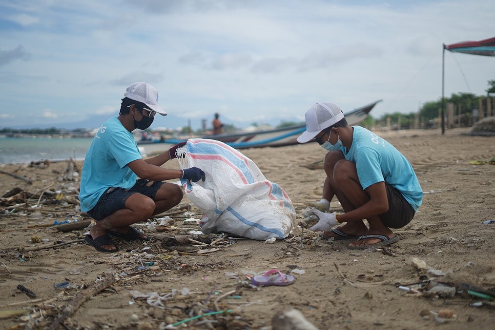 Two young volunteers cleaning up trash on a beach
