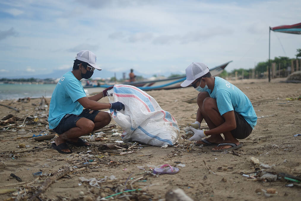 Two young volunteers cleaning up trash on a beach