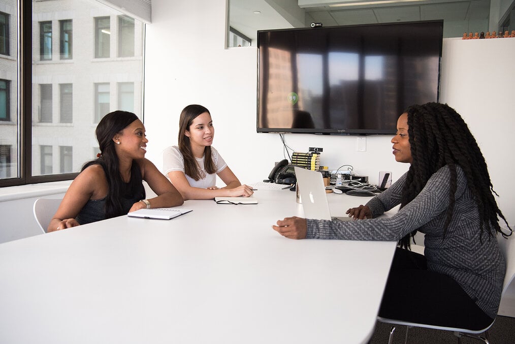 Three people sitting at a desk talking