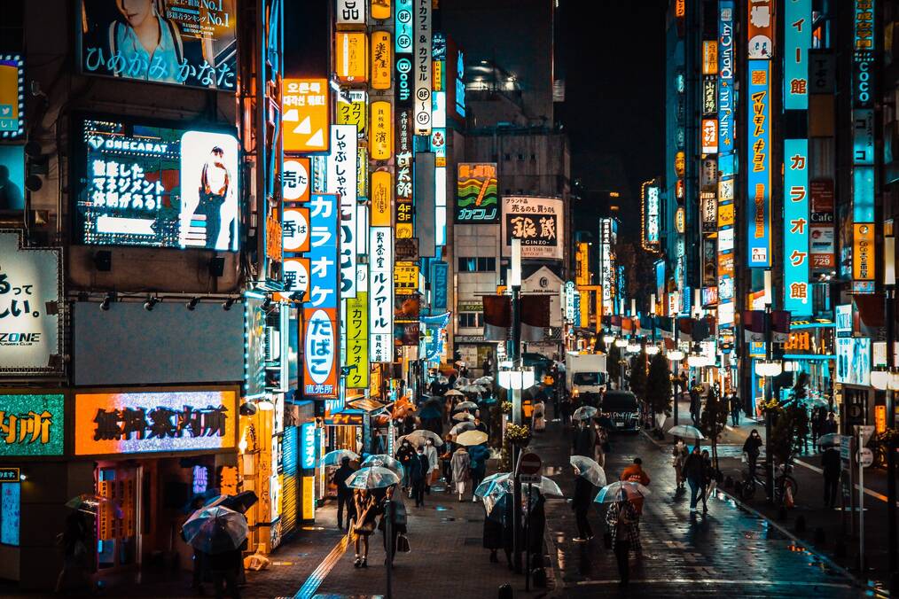 A busy street with neon signs at night in Japan.