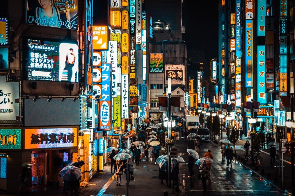 Photo by Pema Lama on Unsplash A busy street with neon signs at night in Japan.