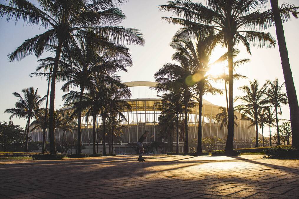 A student skateboarding under palm trees in Durban, South Africa