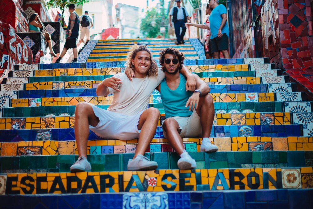 Image curtesy of Elizeu Dias, Unsplash Two friends with their arms around each other smiling on colorful tile steps in Barcelona