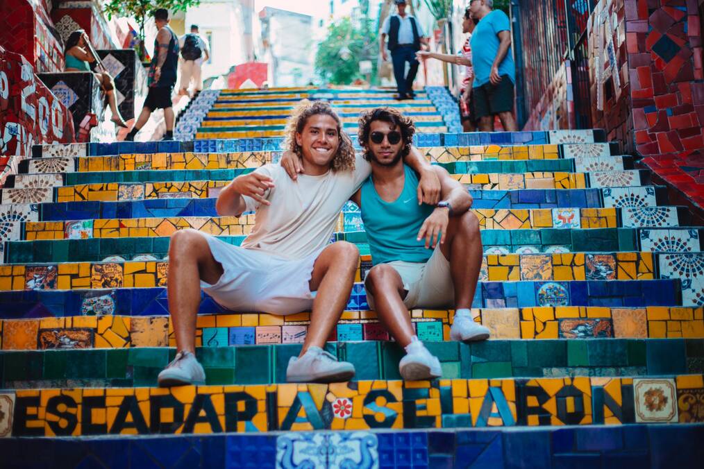 Two friends with their arms around each other smiling on colorful tile steps in Barcelona 