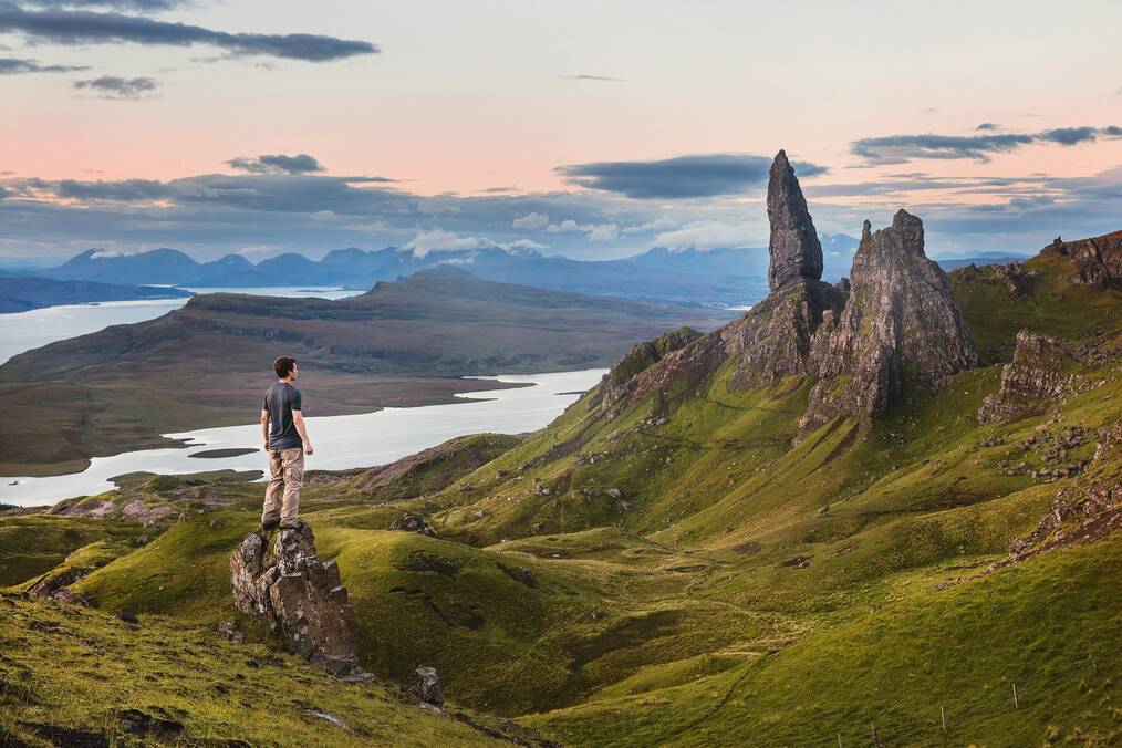 A person standing on a rock looking out a rock points in Scottish highlands